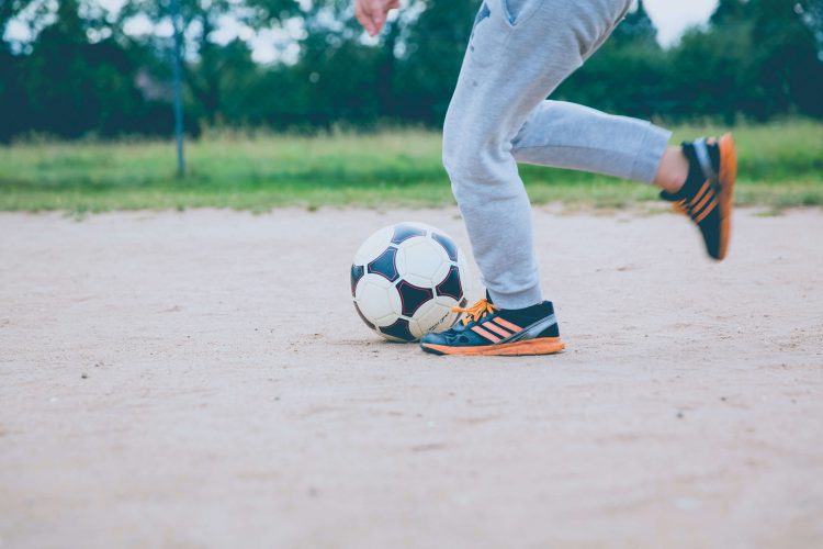 Criança brincando de Futebol Photo by Markus Spiske on Unsplash