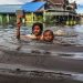 Crianças caminham pela água da enchente na Indonésia Foto :Greenpeace /Pram
