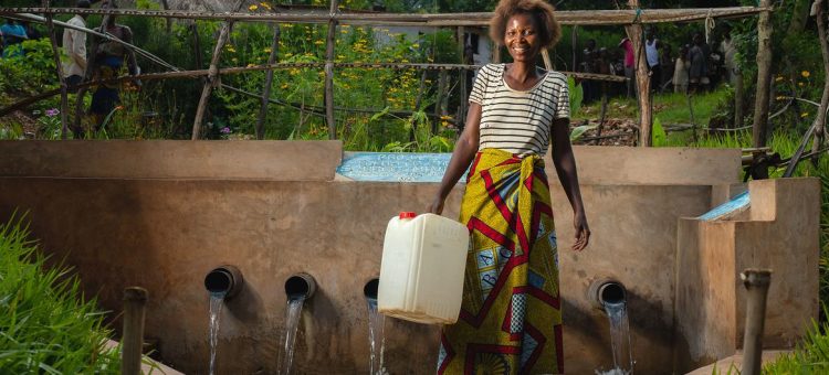 Mulher recolhe água numa fonte desenvolvida pelo Unicef na República Democrática do Congo - Foto: Unicef/Gwenn Dubourthoumi