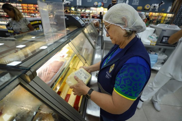 Servidora da Visa Manaus fiscalizando produtos alimentícios em supermercado durante a operação “Natal com Saúde”