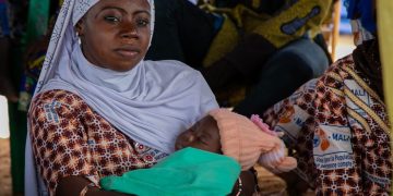 Uma mulher com seu bebê ouve a equipe do UNFPA em uma sessão de conscientização sobre violência de gênero no One Stop Centre do Hospital Sominé Dolo. - Foto: