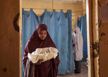 Uma mulher segura um bebê recém-nascido dentro da ala de trabalho de parto de um hospital no estado de Sokoto, Nigéria. Foto: UNICEF/David Boman